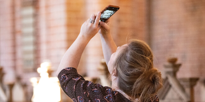 Kvinde tager billede af loftet i en kirke med sin mobiltelefon